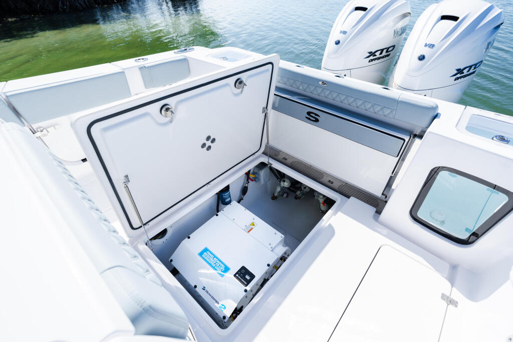 Open compartment displaying electronics and storage with dual XTR engines and livewell visible on white center console boat