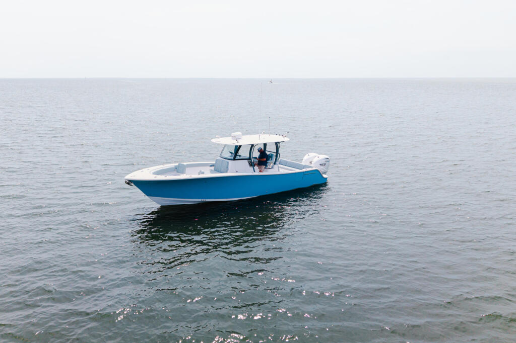 Blue and white center console boat running offshore in calm water
