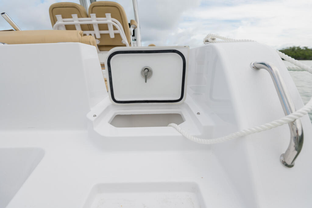 White fiberglass storage locker with locking hatch and rope cleat on boat stern