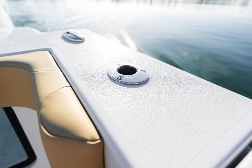 Close-up of white boat gunwale with ventilation ports and calm water beyond