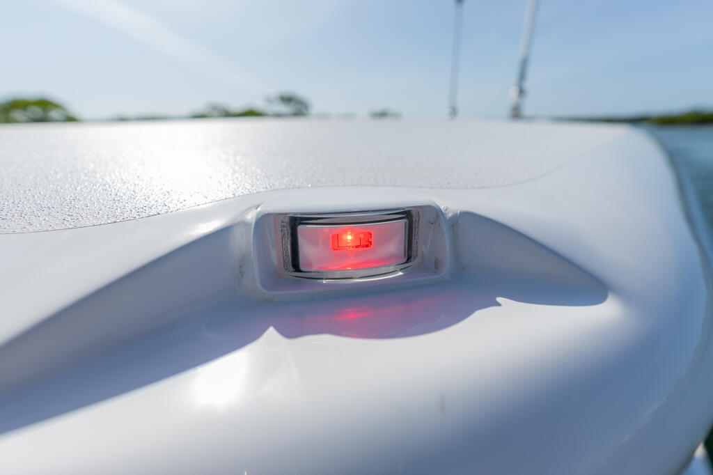 Red navigation light fixture mounted on the white gunwale of a center console boat