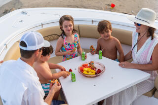 Family enjoying snacks and drinks together at a table inside a boat cabin