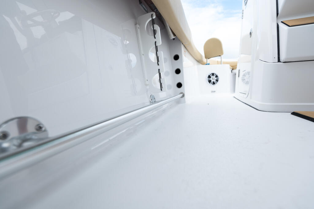 Clean white cabin interior with toe rail, cabin door, ventilation, and tan seating visible