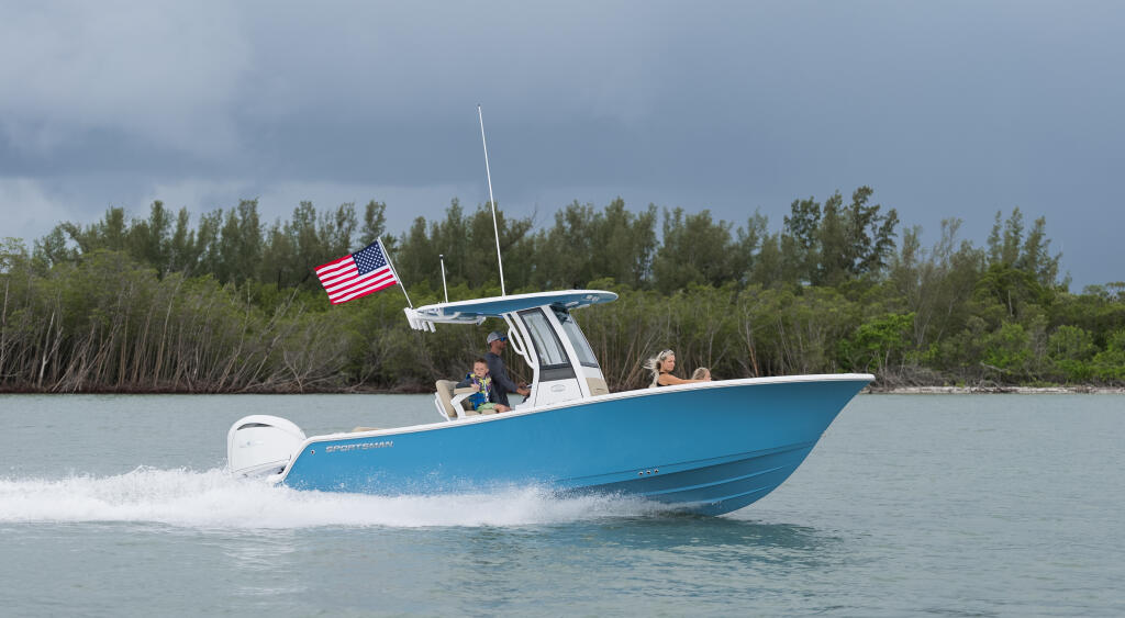 Blue and white center console boat running near mangroves with American flag and passengers aboard
