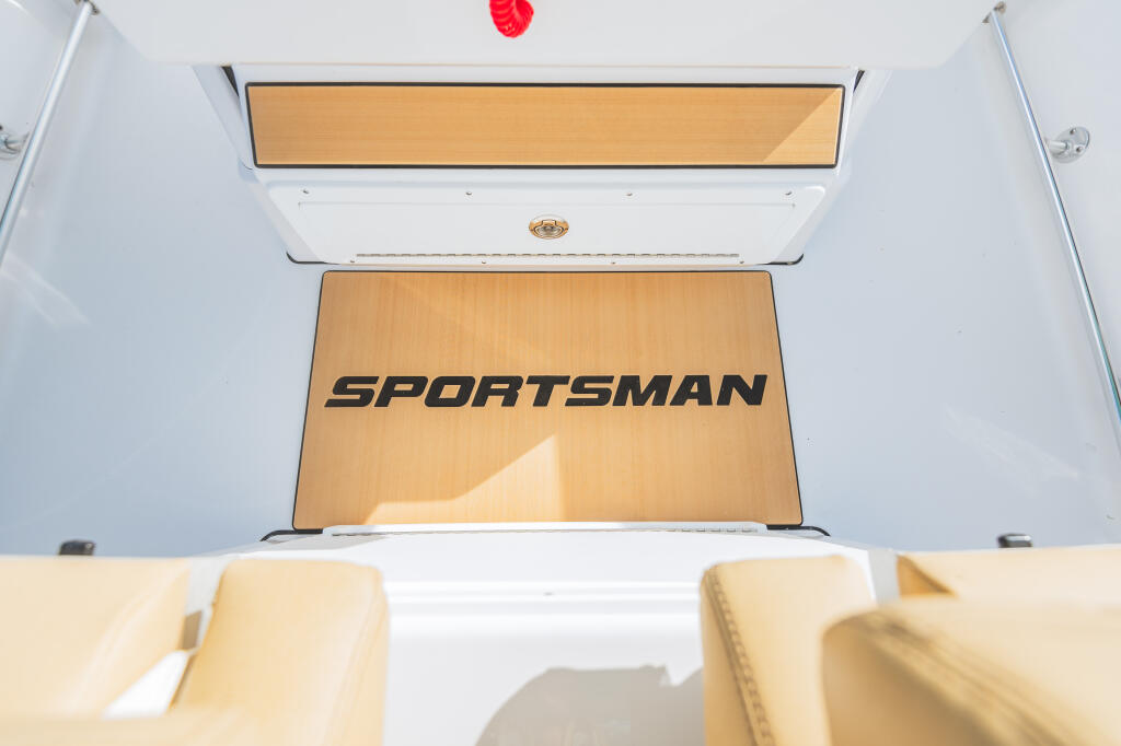 Sportsman boat cabin interior with cream-colored seating, wooden accents, and overhead storage compartments