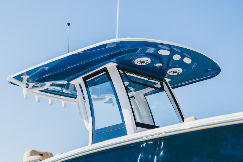 Overhead view of a blue and white boat's hard-top canopy with dashboard instruments and windshield against clear sky
