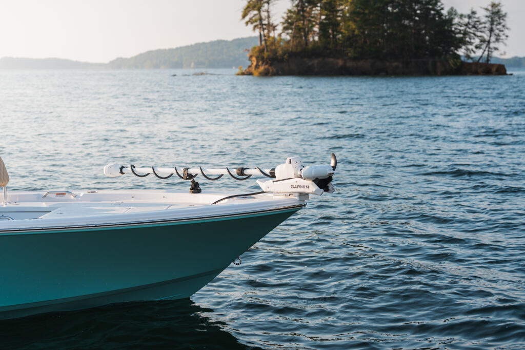 Fishing boat with Garmin trolling motor anchored offshore near forested shoreline