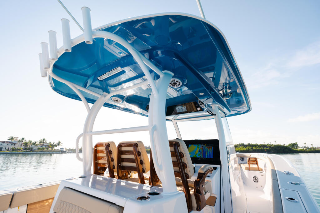 Modern fishing boat with blue hard-top canopy, brown seating, and electronics display docked in calm waters