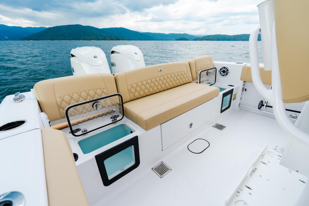 Spacious boat cockpit with tan quilted seating, dual engines, and mountains across the water