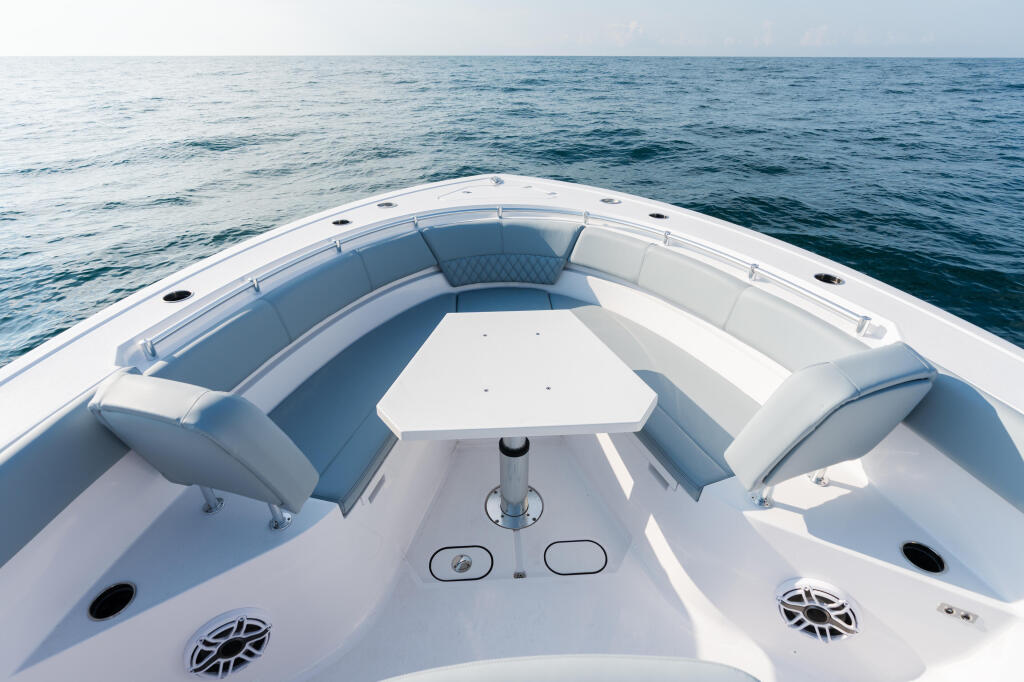 Bow seating area of a center console boat with blue cushioned seats and white fiberglass hull overlooking calm open ocean