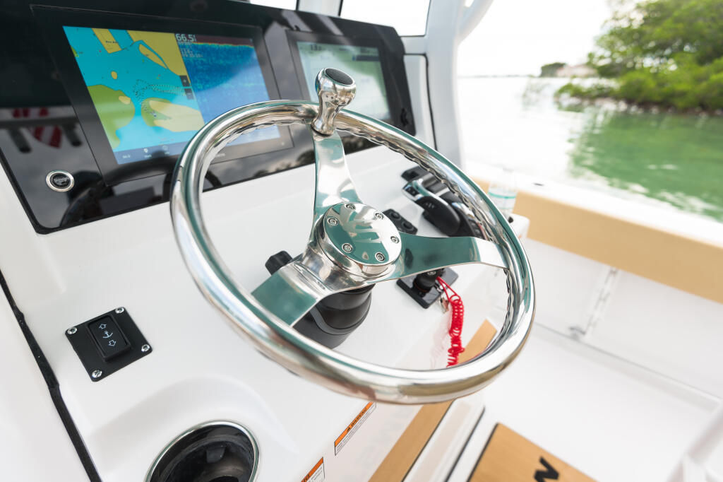 Polished stainless steel steering wheel with tilt helm at boat console, GPS display visible above