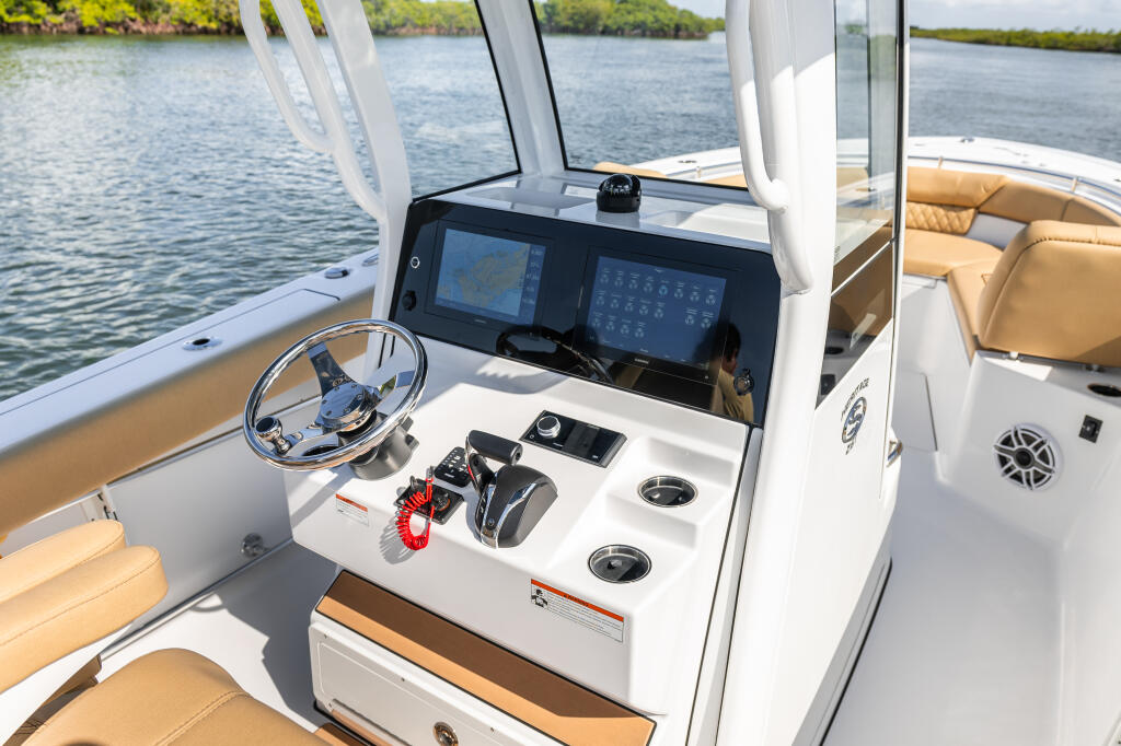Helm station with dual Garmin GPS chartplotters, steering wheel, and center console controls overlooking calm waterway