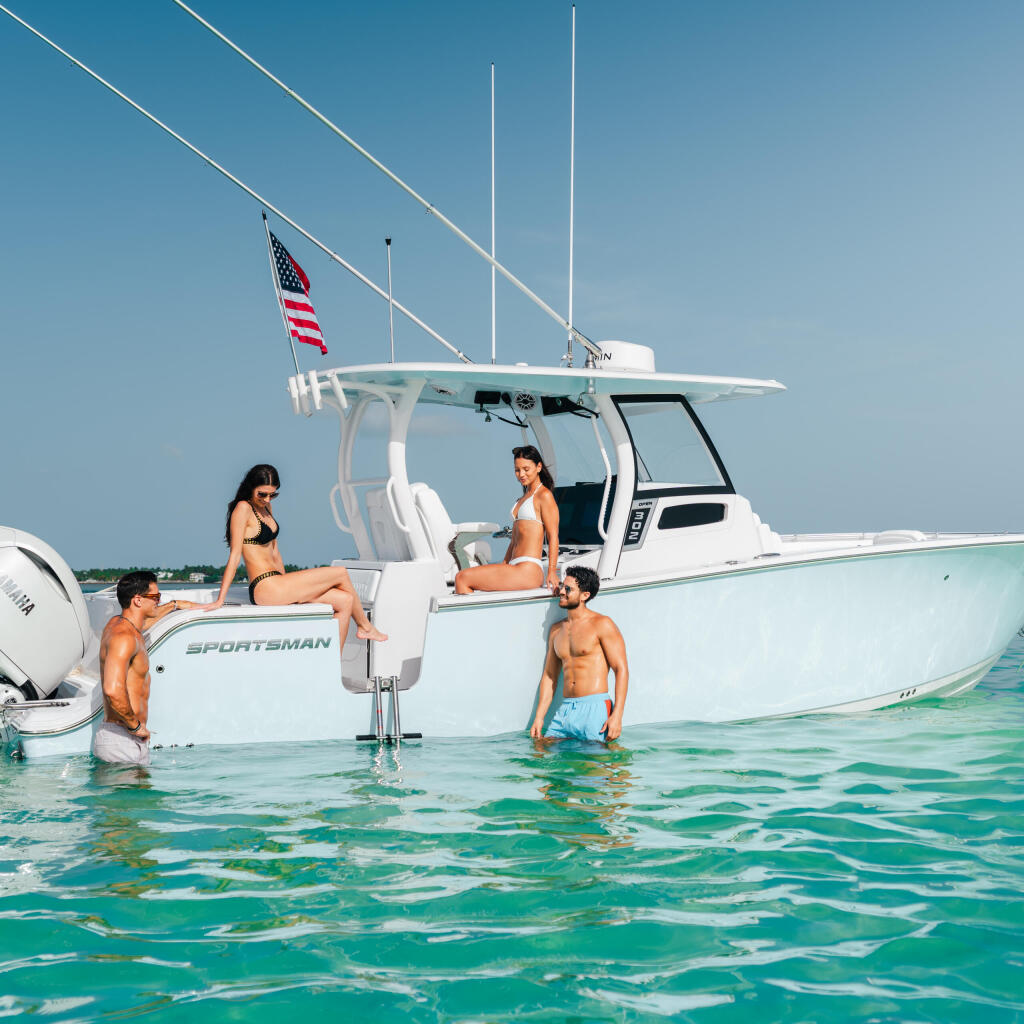 Group of friends swimming and relaxing around a white Sportsman center console boat in turquoise shallow water