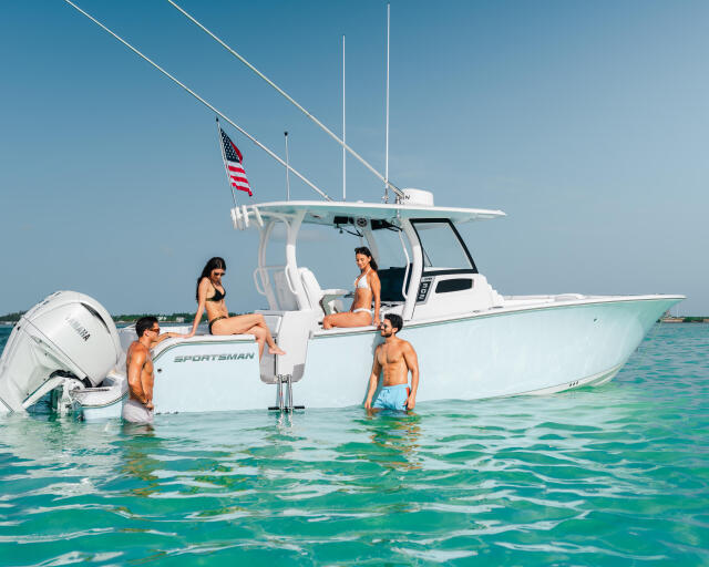 Group of friends swimming and relaxing around a white Sportsman center console boat in turquoise shallow water
