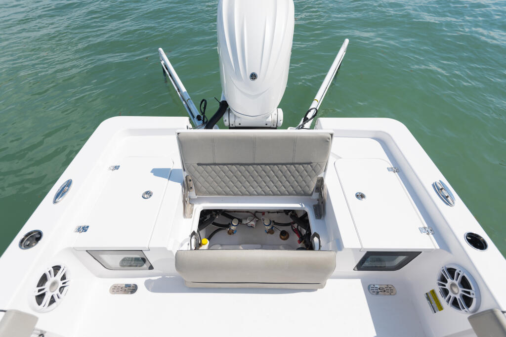 Overhead view of boat's open engine hatch with padded seat, dual outboard engines, and electronics visible from stern
