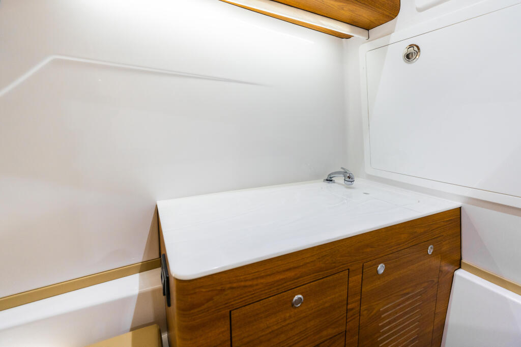 Compact boat cabin with wooden cabinetry, white countertop, and storage lockers
