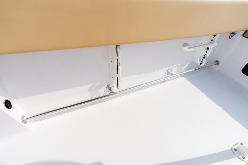 Clean white boat deck with chrome rod holder and tan hardtop canopy overhead