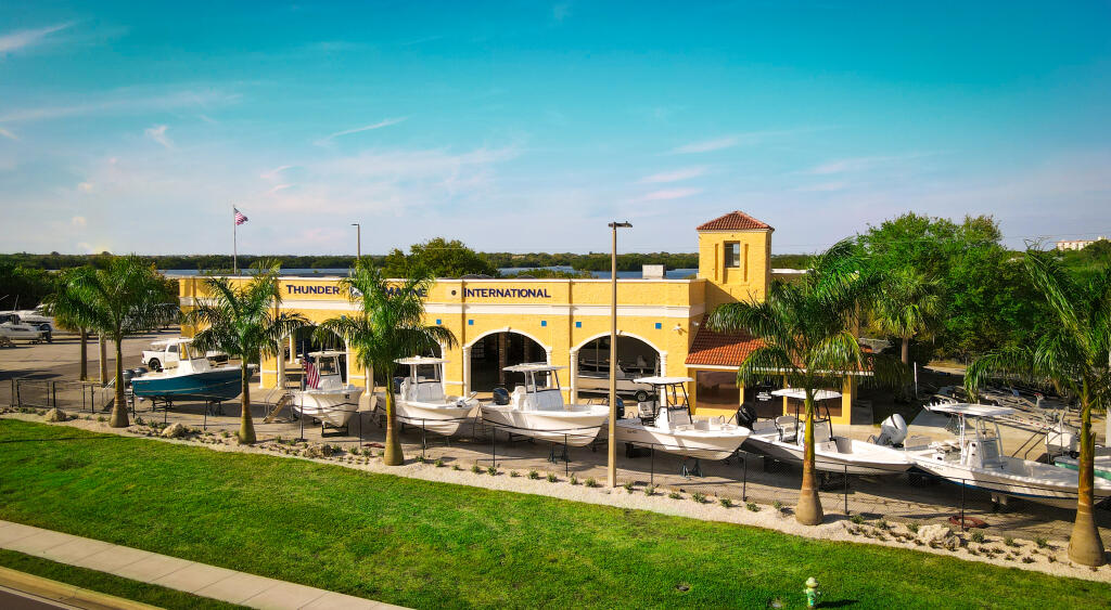 Thunder Marine dealership storefront with yellow building and docked boats along waterfront