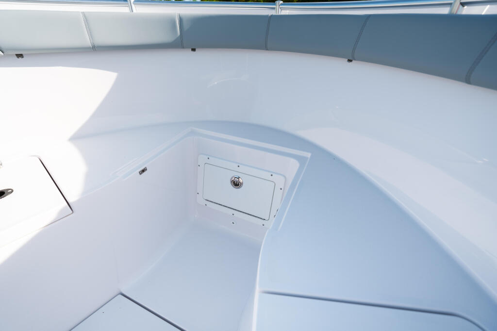 Clean white boat deck with storage compartment and blue seating visible along the gunwale