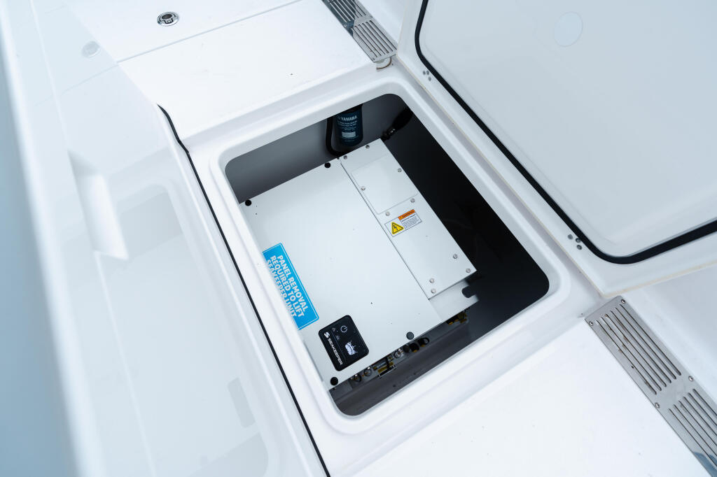 Boat electronics and control panel mounted in white console with wiring and safety labels visible