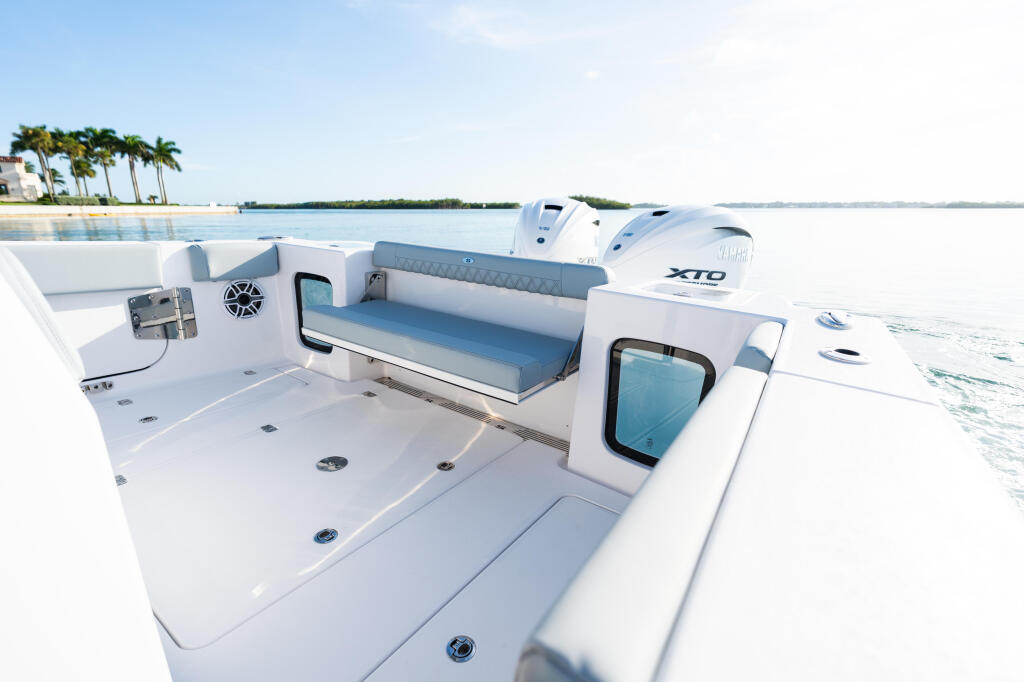 Open 322 boat cockpit with blue upholstered seating, white console, and calm water with palm trees in background