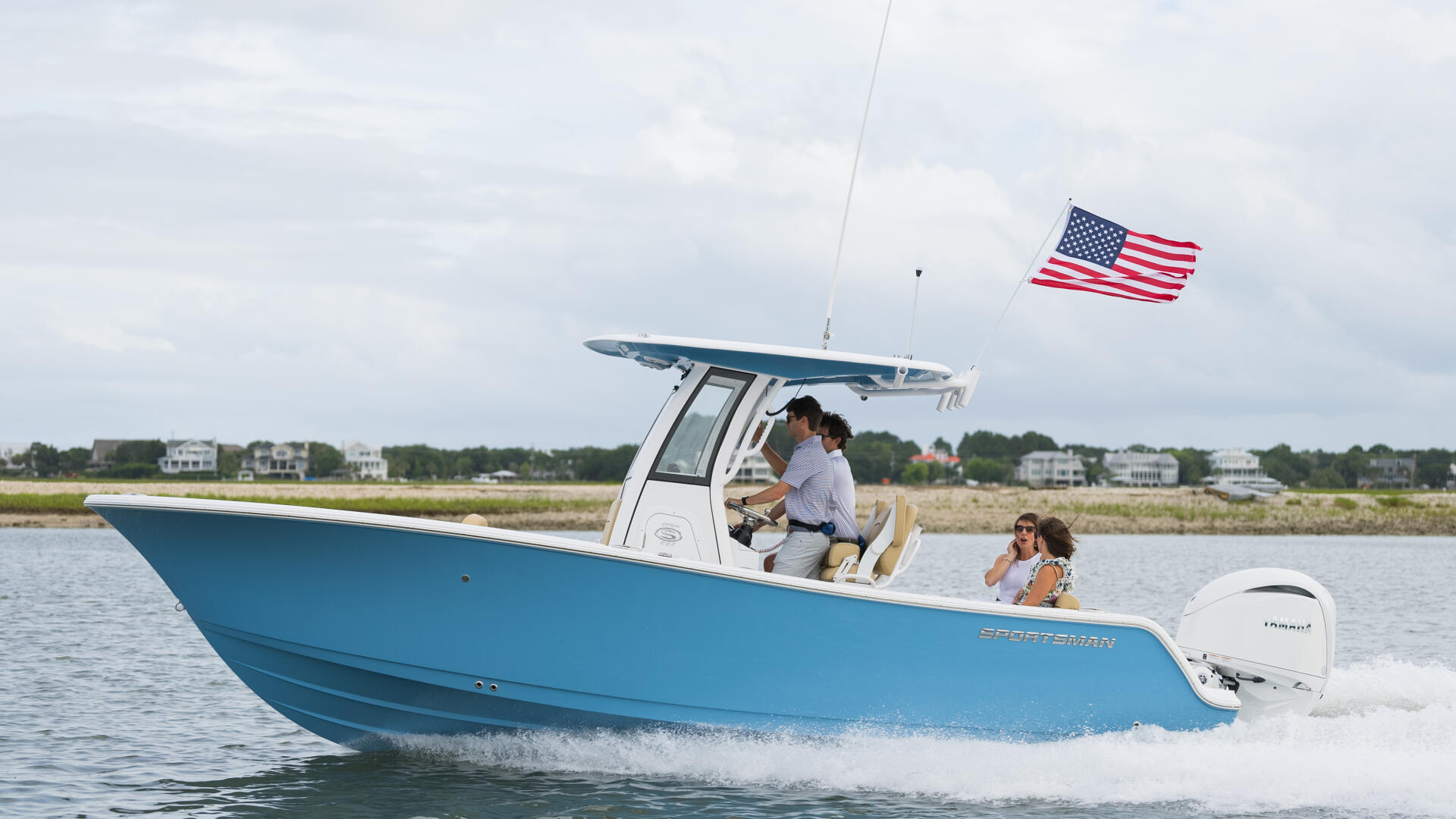Blue and white sportsman boat with American flag running through shallow coastal waters with passengers aboard