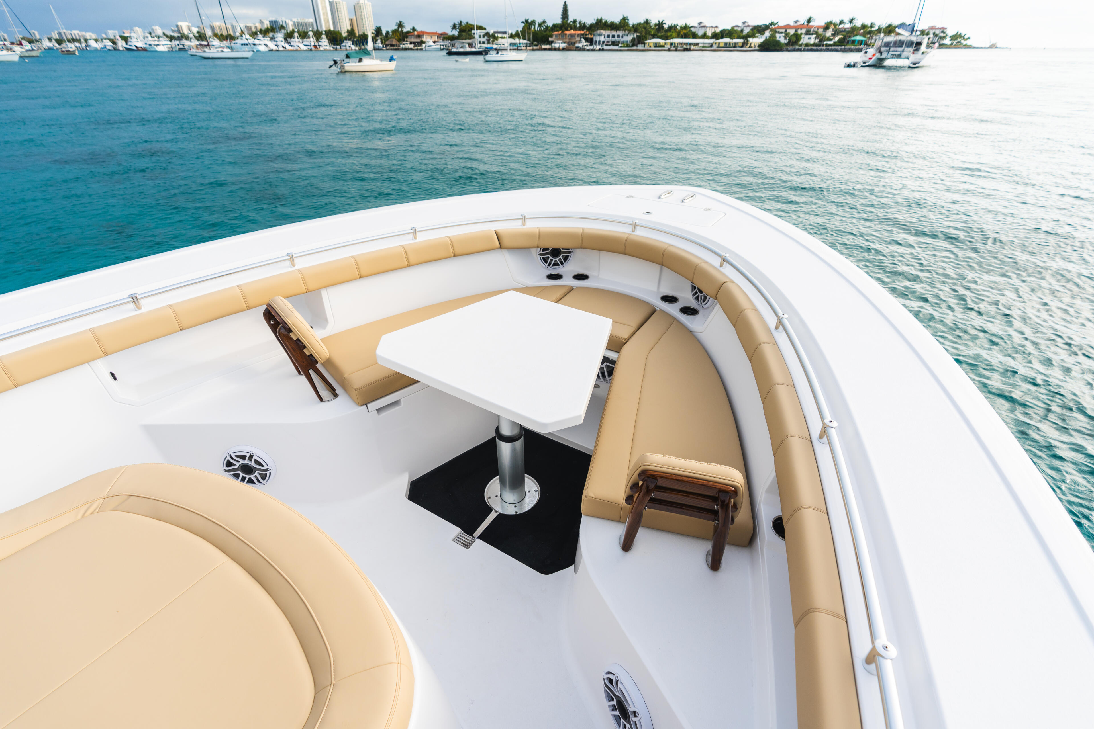 Spacious forward seating area with cream cushioned lounge and table, anchored in turquoise marina waters