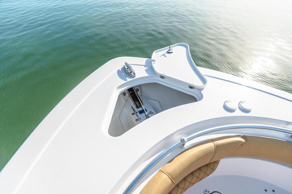 Overhead view of boat's anchor windlass and cabin access with turquoise water alongside
