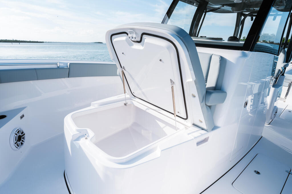 Open livewell with hinged lid on the bow of a center console boat with water and sky visible