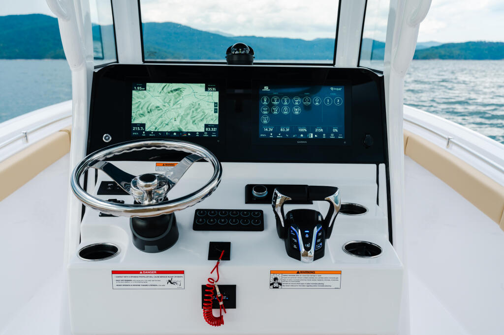 Helm station with dual monitors displaying navigation and system controls overlooking a mountain lake