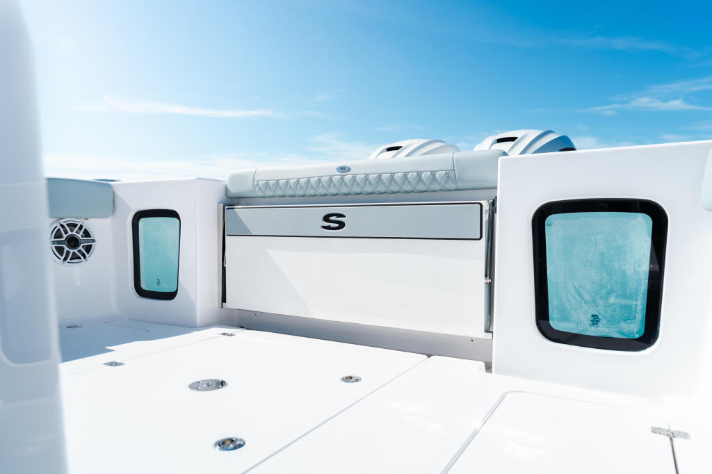 Spacious open boat deck with dual helm seating, storage compartments, and large windows under clear blue sky