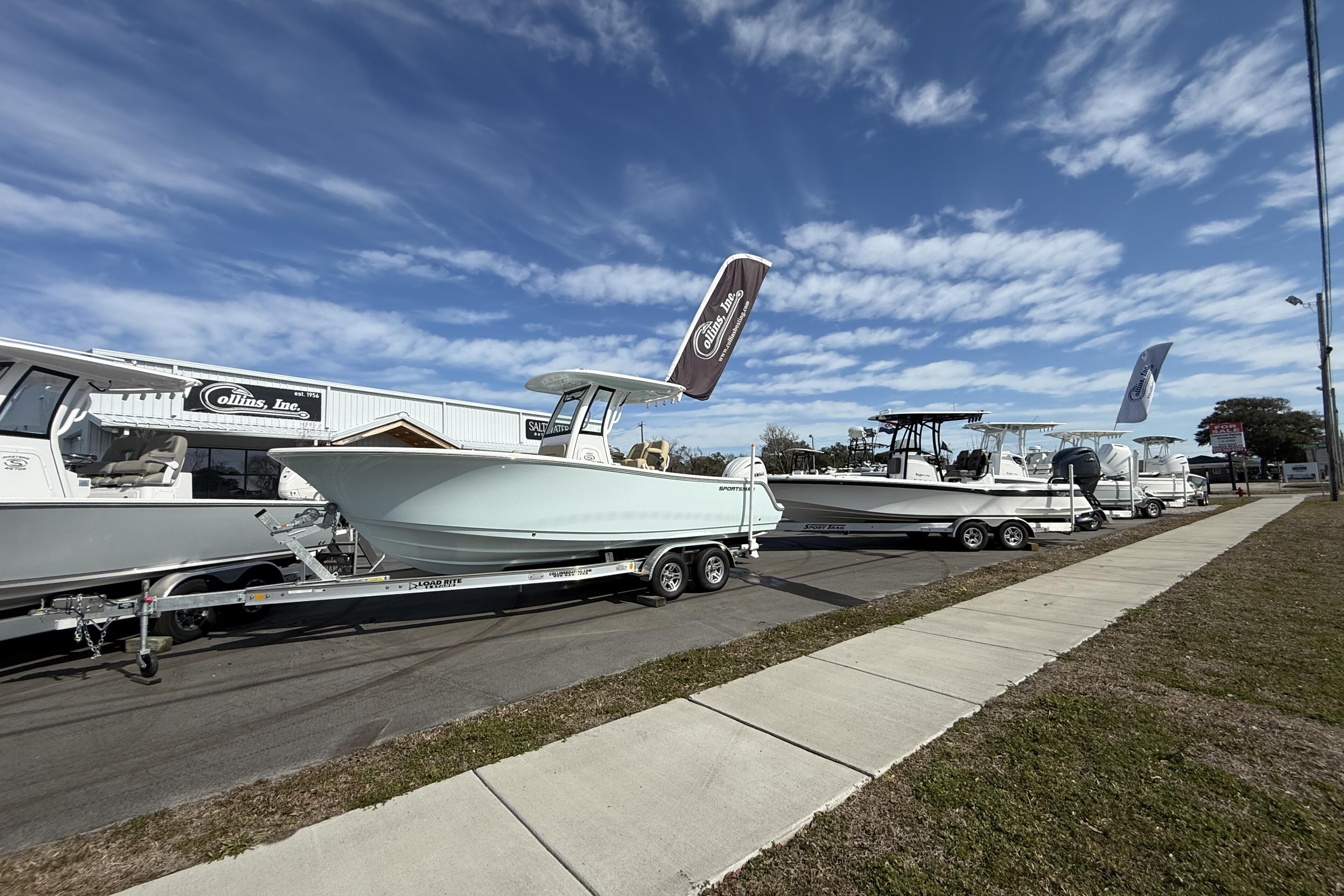 Multiple boats on trailers displayed at a marina dealership with Collins Inc storefront building