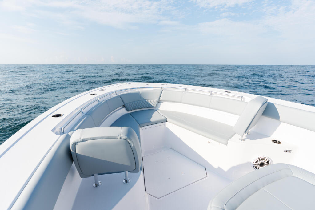 White center console boat with gray cushioned seating on calm open ocean under clear sky