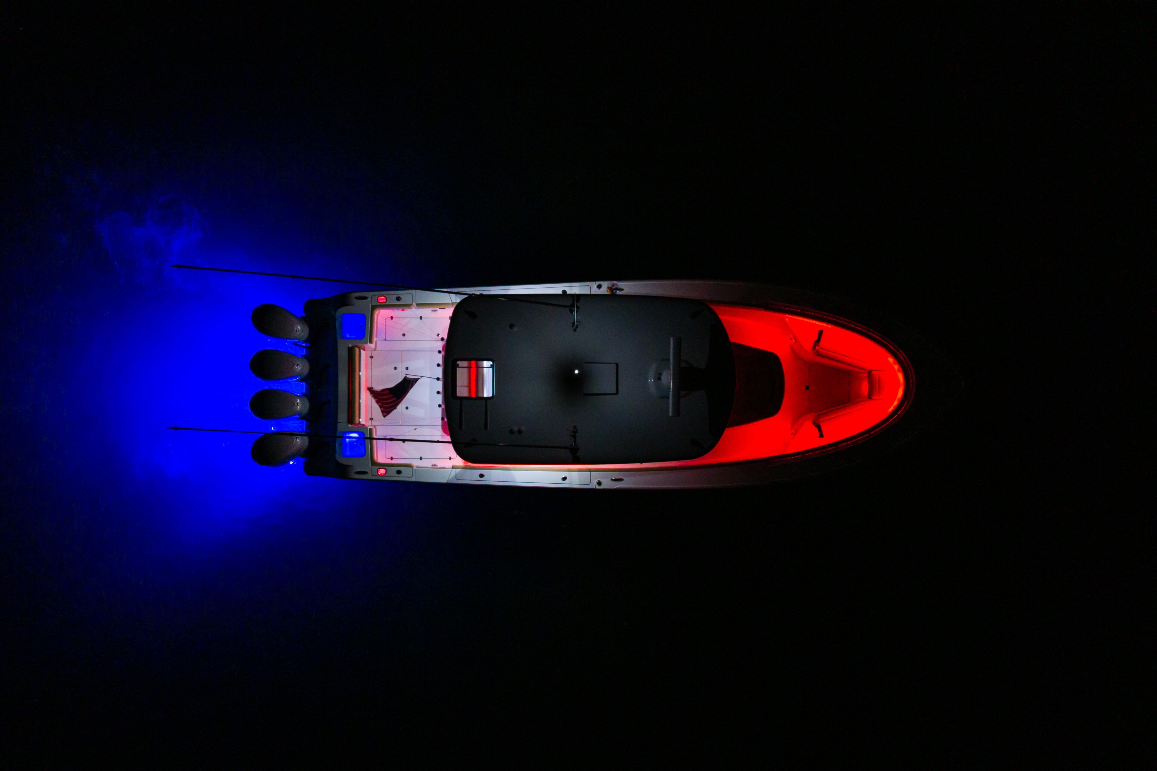 Red and black center console boat viewed from above with blue RGB lighting illuminating the water