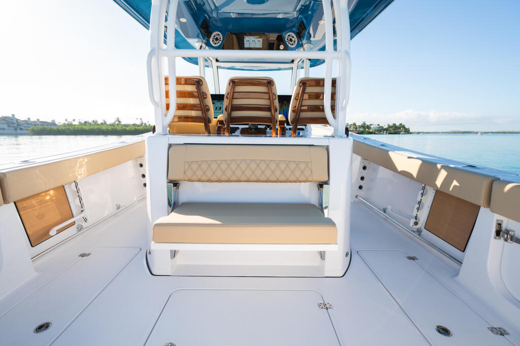 Overhead view of boat cockpit with tan cushioned seating, center console, and open cabin door revealing helm area