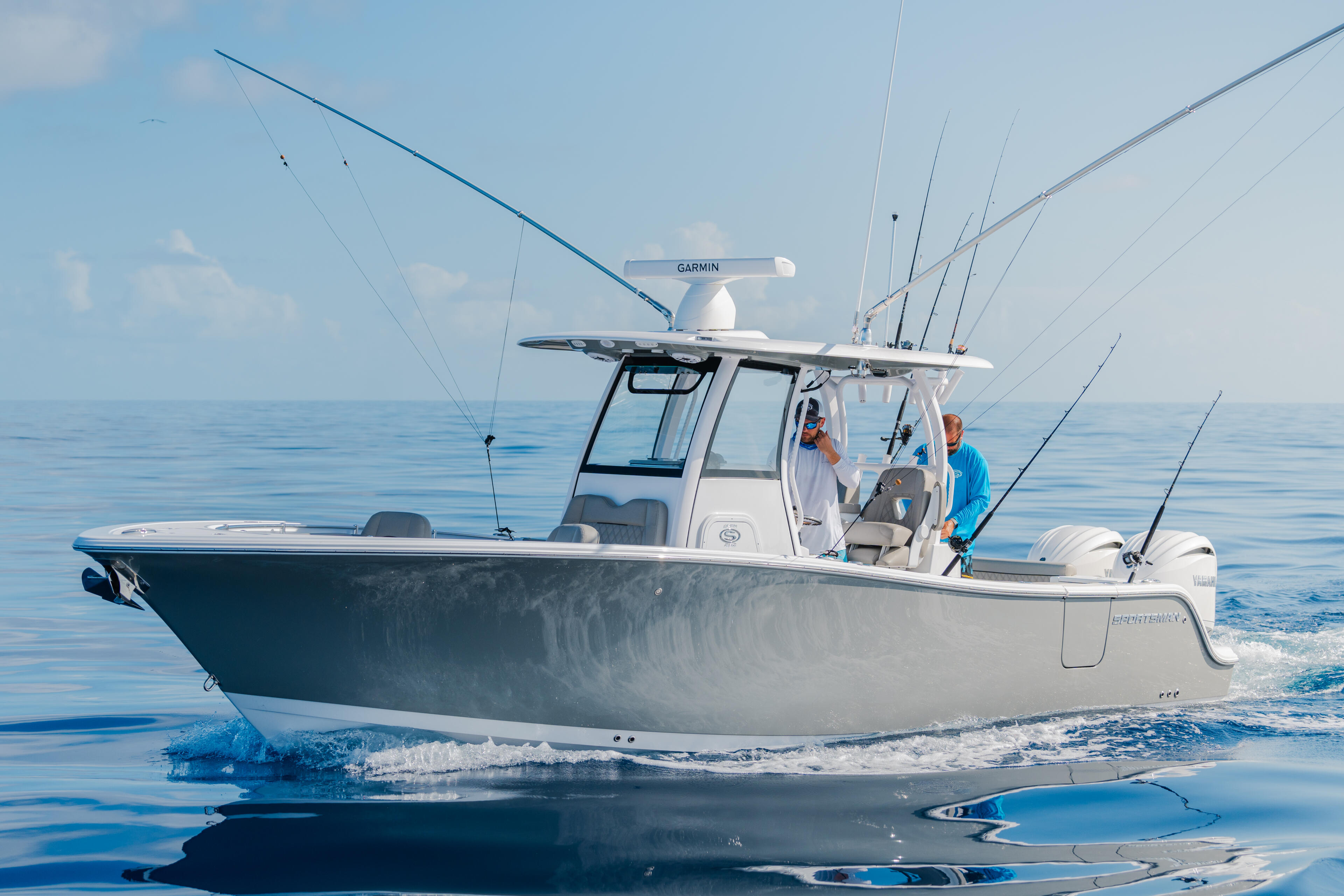 Fishing boat with hard-top running offshore in calm blue water with multiple fishing rods mounted