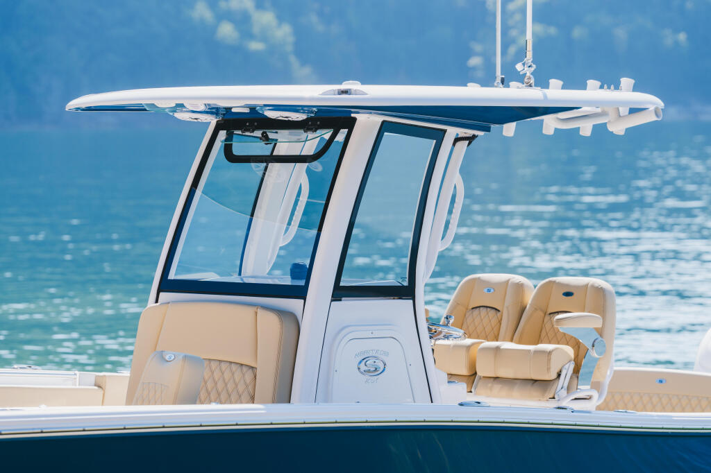 Hard-top cabin cruiser with tan leather seating and windshield, floating on calm turquoise water