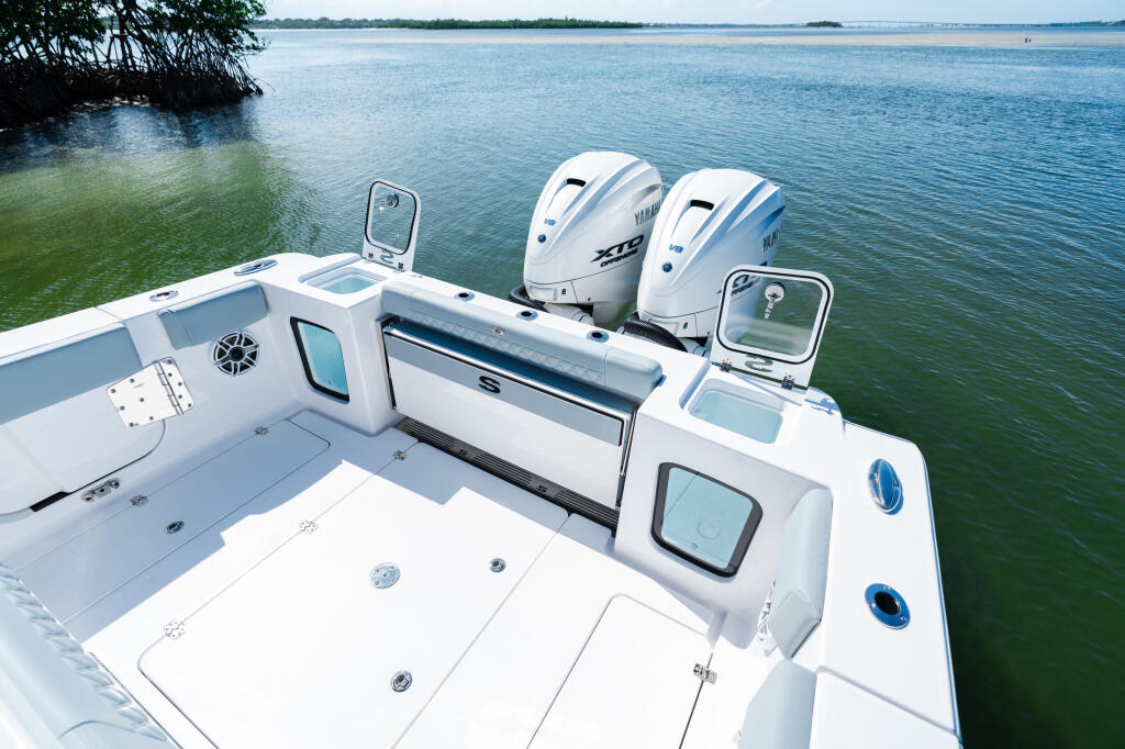 Dual outboard engines and helm electronics on an Open 322 fishing boat docked in shallow coastal waters
