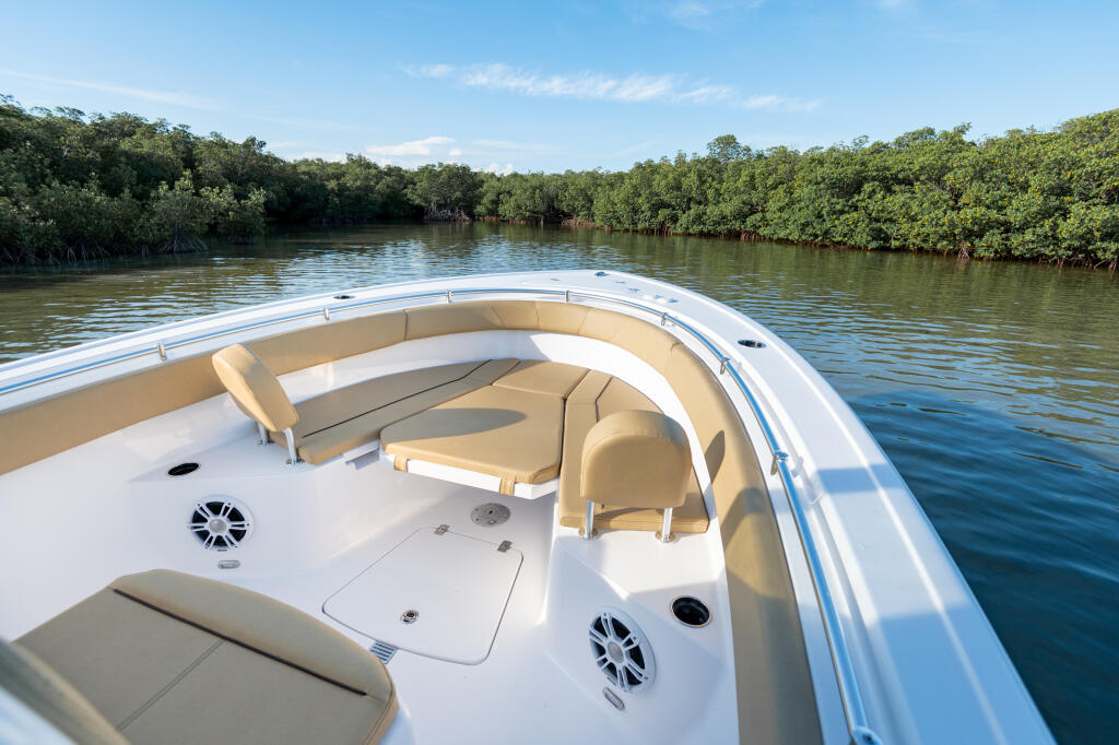 Helm view of open bow cabin cruiser with tan seating and storage cruising through mangrove waterway