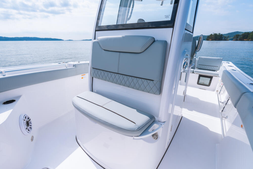 Center console helm seat with gray upholstered backrest and white base on calm lake waters