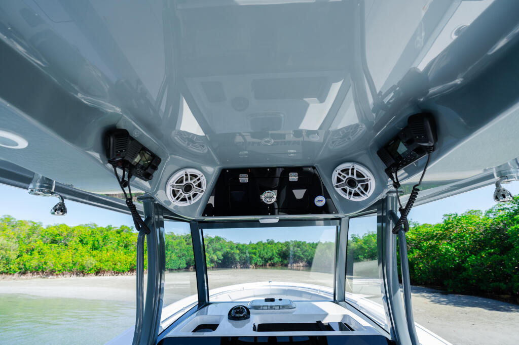 View from inside the hard-top looking forward toward the windshield, helm, and shallow mangrove-lined waters ahead