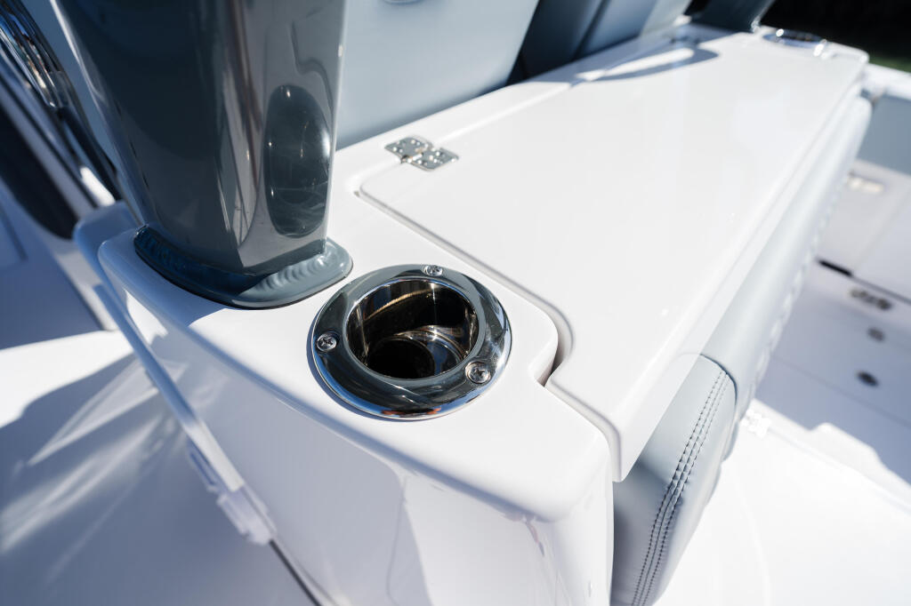 Close-up of chrome deck hardware and white fiberglass gunwale detail on a boat