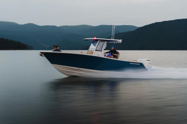Sportsman center console boat running across calm lake with forested mountains in background
