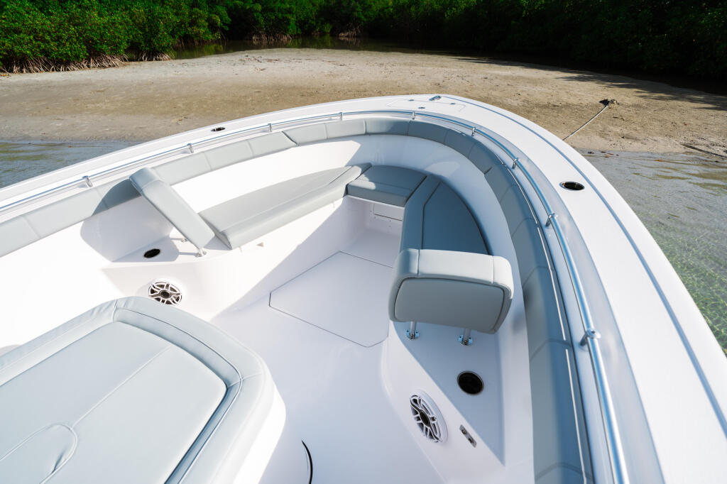 Open 322 center console with cushioned seating and storage, beached on sandy shore with mangroves beyond