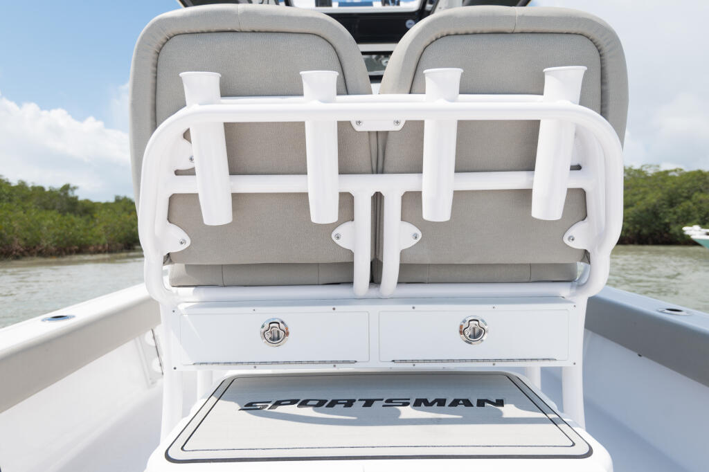 Rear seating area of Sportsman boat with gray upholstered seats, white safety rails, and storage compartments