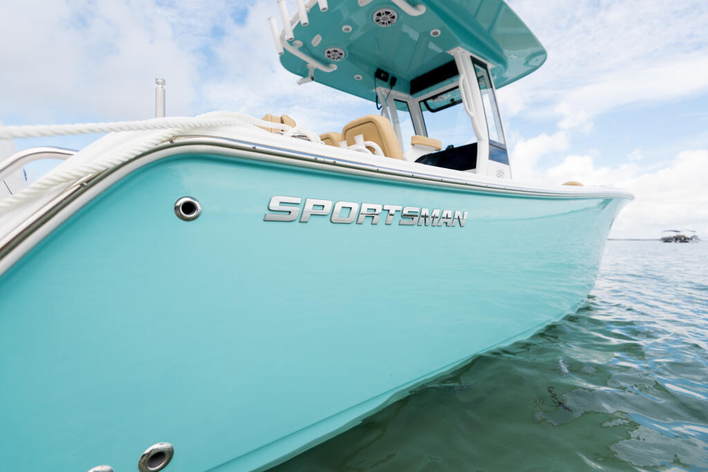 Turquoise Sportsman center console boat with hard-top and tan seating at rest in shallow water