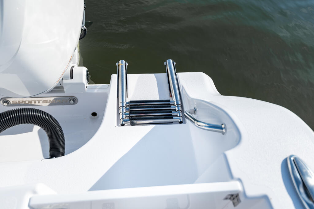 Stainless steel boarding ladder mounted on white fiberglass transom of Sportsman center console boat