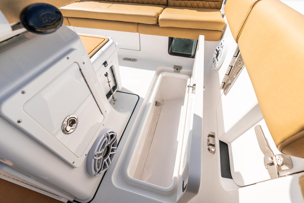 Overhead view of boat's in-deck fish boxes and helm area with tan upholstery and white gel coat