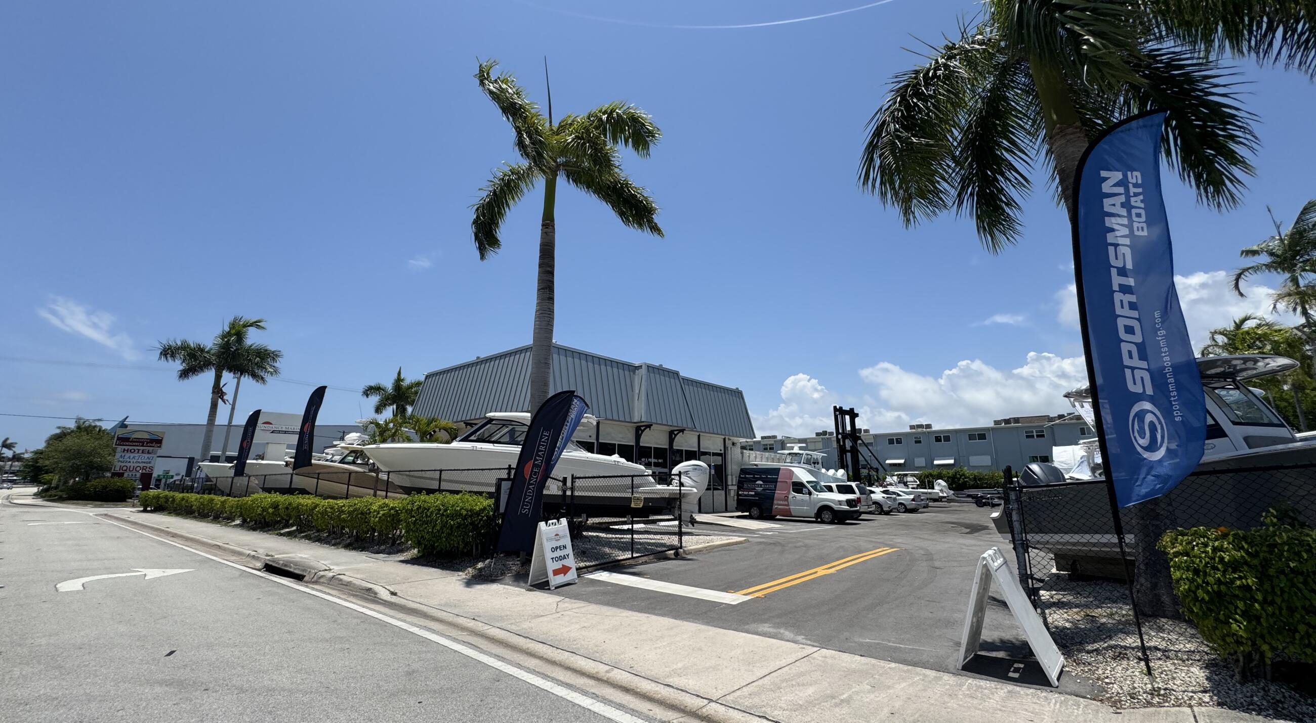 Sportsman Boats dealership storefront with boats displayed in a palm-tree lined marina lot