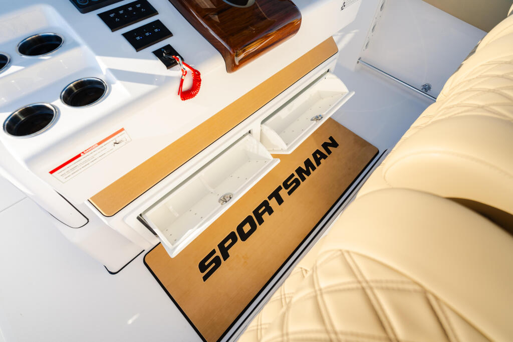 Overhead view of Sportsman boat helm area with electronics panel, tan cushioned seating, and storage compartments